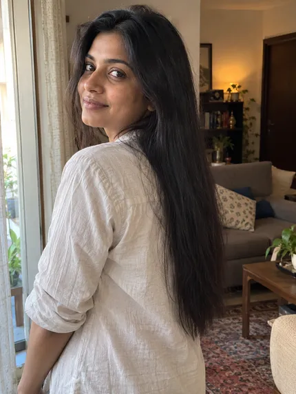 Woman with long black hair by a living room window