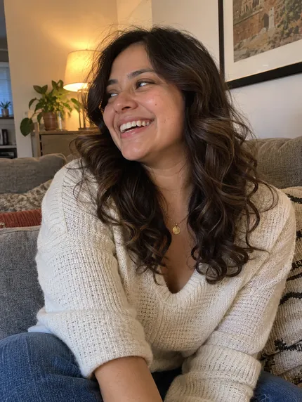 Woman with loose dark curls smiling at home