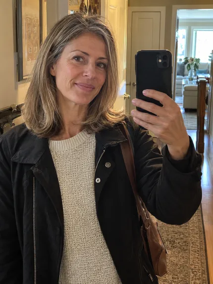 Woman with softly styled dark blonde hair taking a hallway selfie